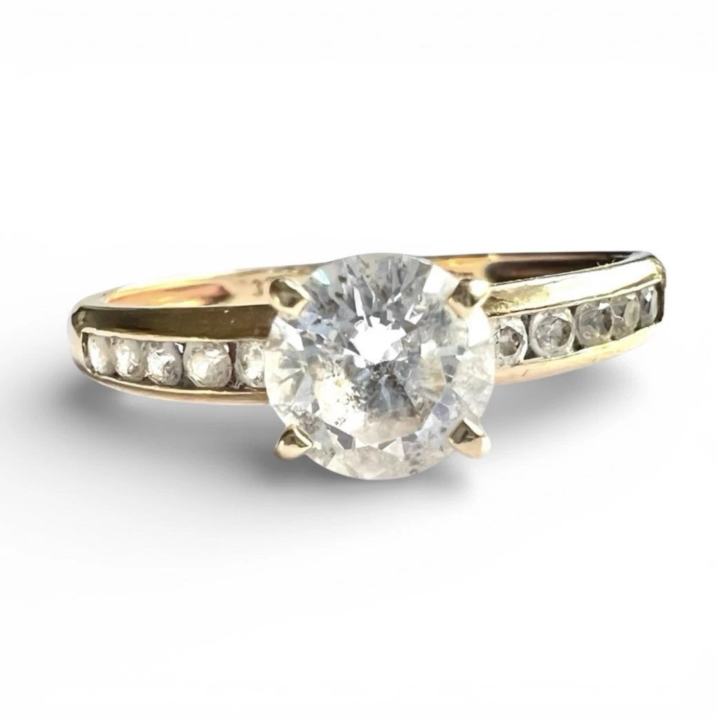 Gold ring with a large CZ and smaller CZ on the band against a white background