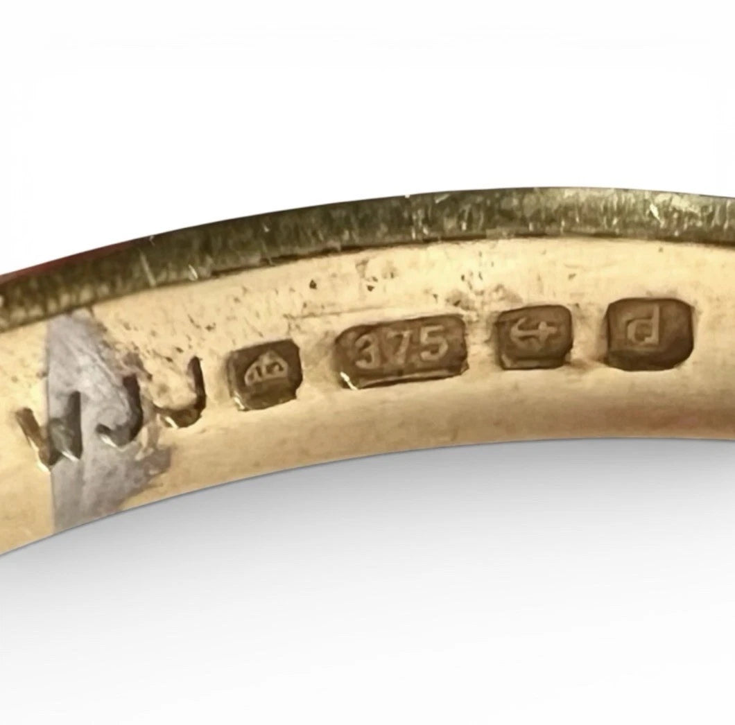 Close-up of a gold ring with engraved hallmark on a white background