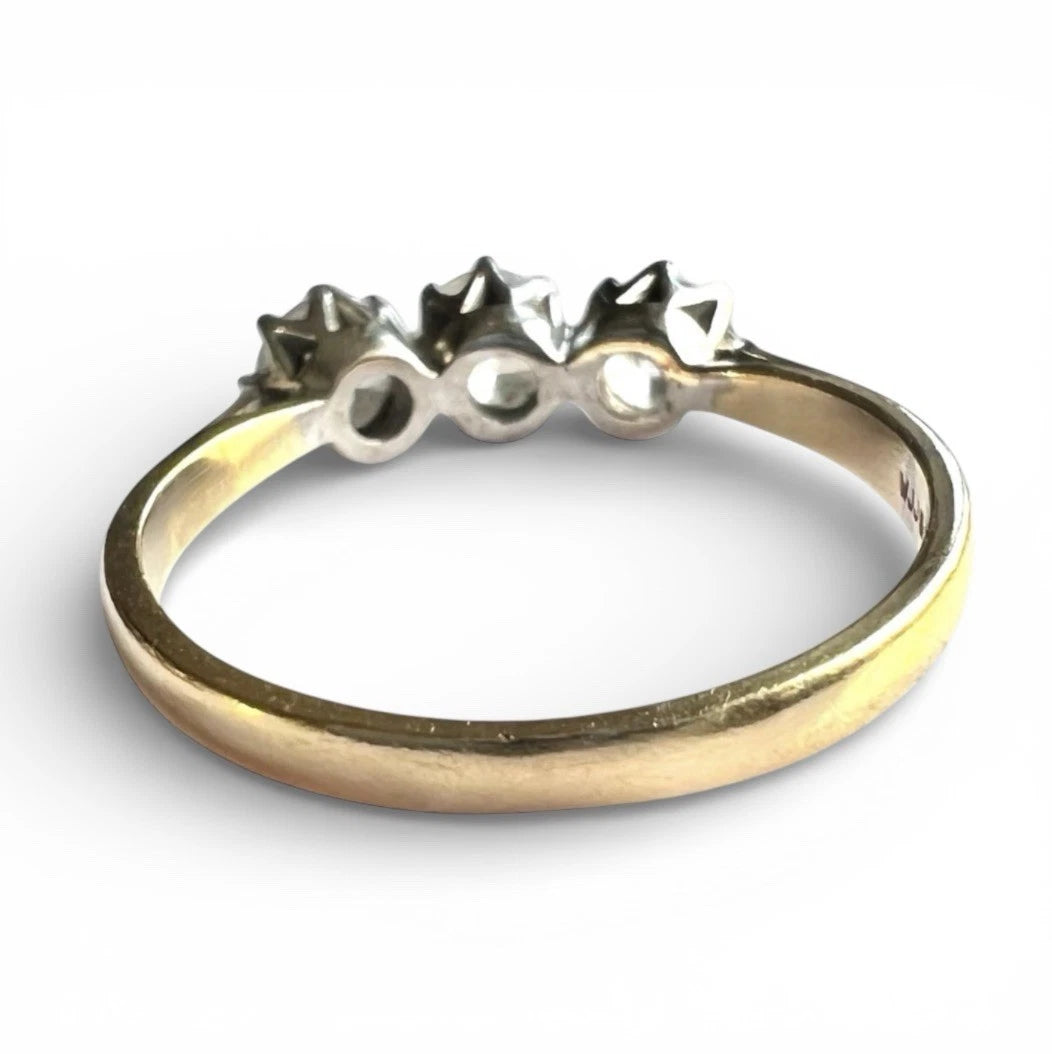 Gold ring with three small diamonds on a white background close up rear view of setting and gold band 