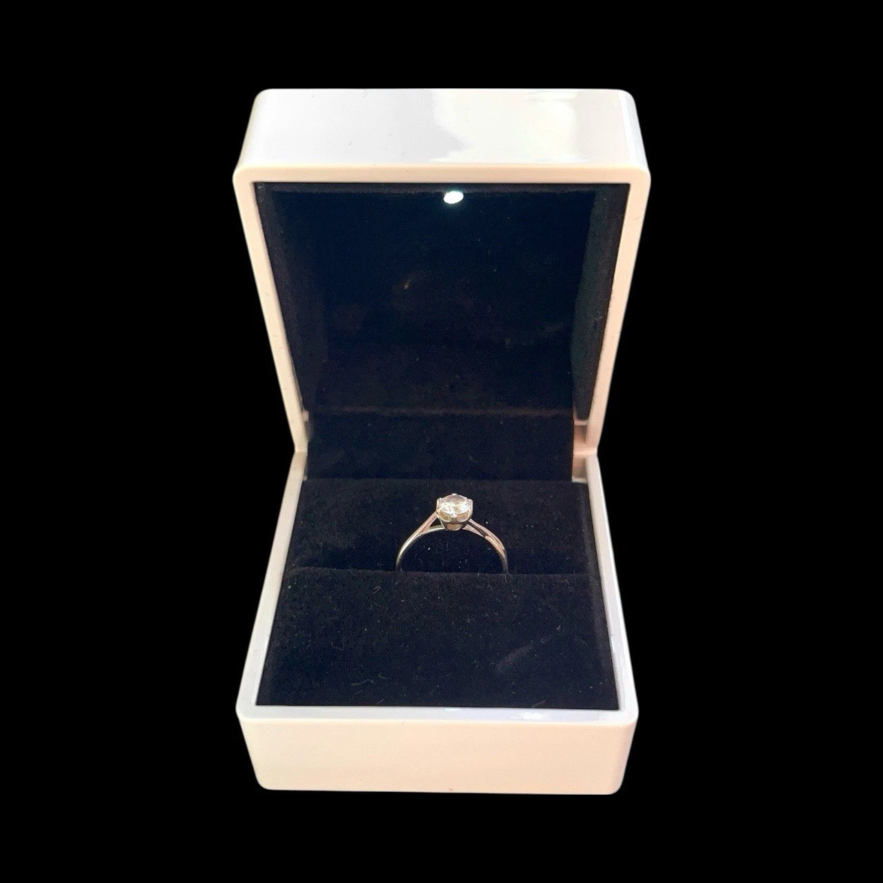 Open jewellery box with a gold ring inside on a black background