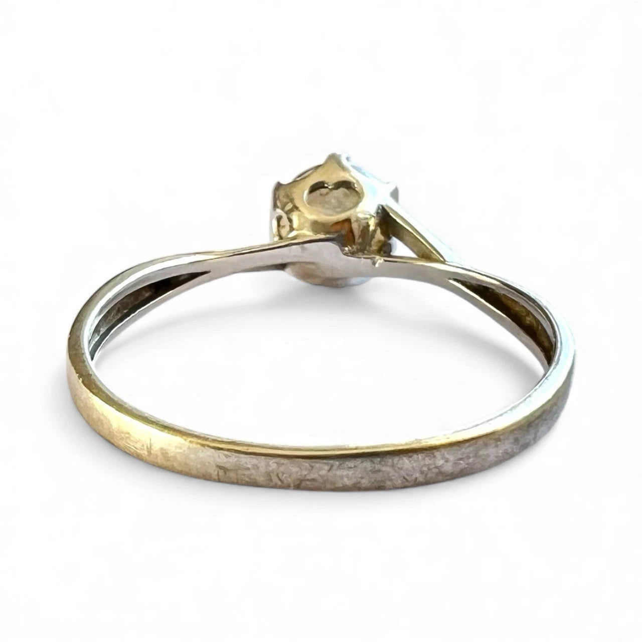 White gold ring with a CZ on a white background, rear view close up of setting and gold band 