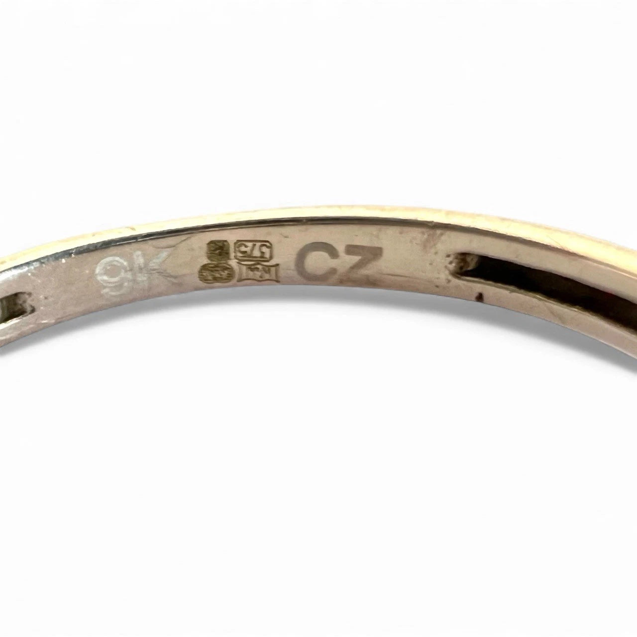 Close-up of a gold ring with hallmark, 'CZ' and '9K' stamping on a white background