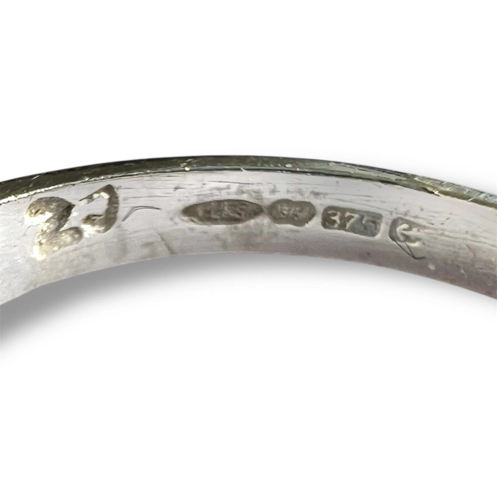 Close-up of a gold ring with engraved hallmark on a white background