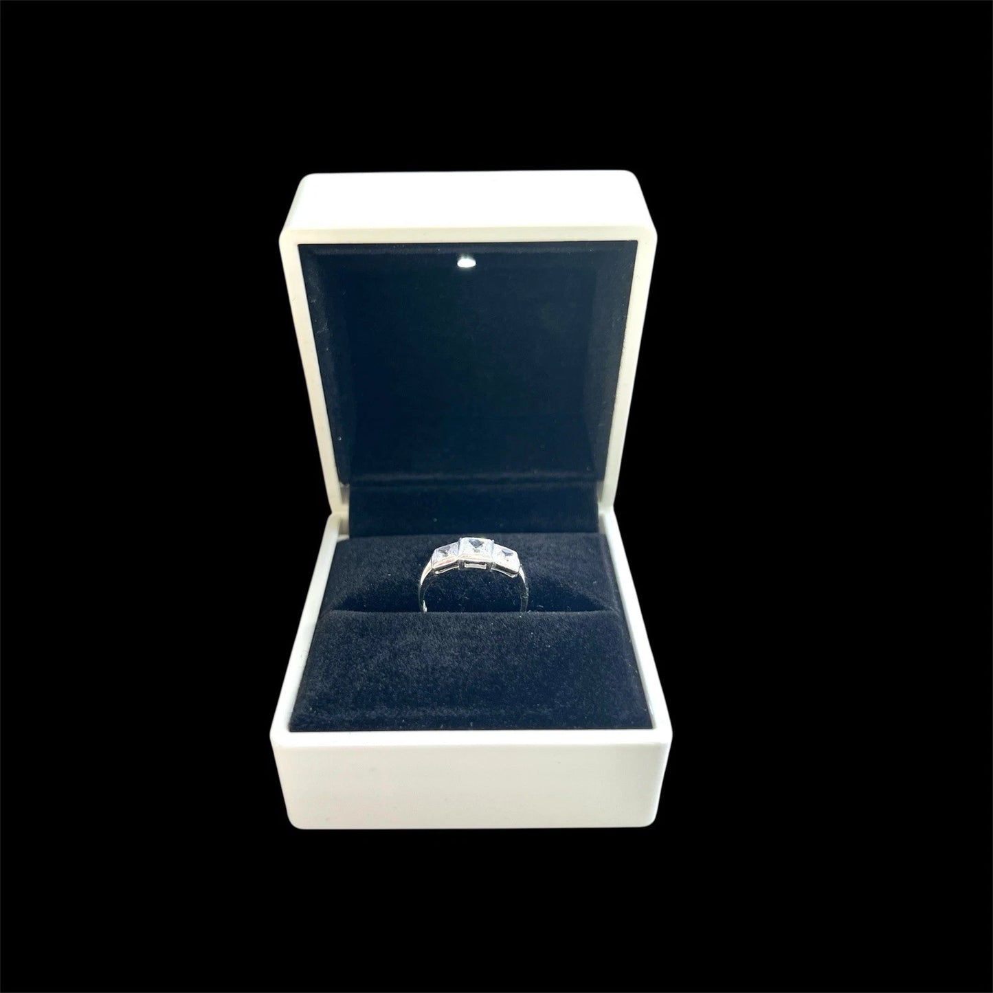 White gold ring in a white jewellery box with a black background