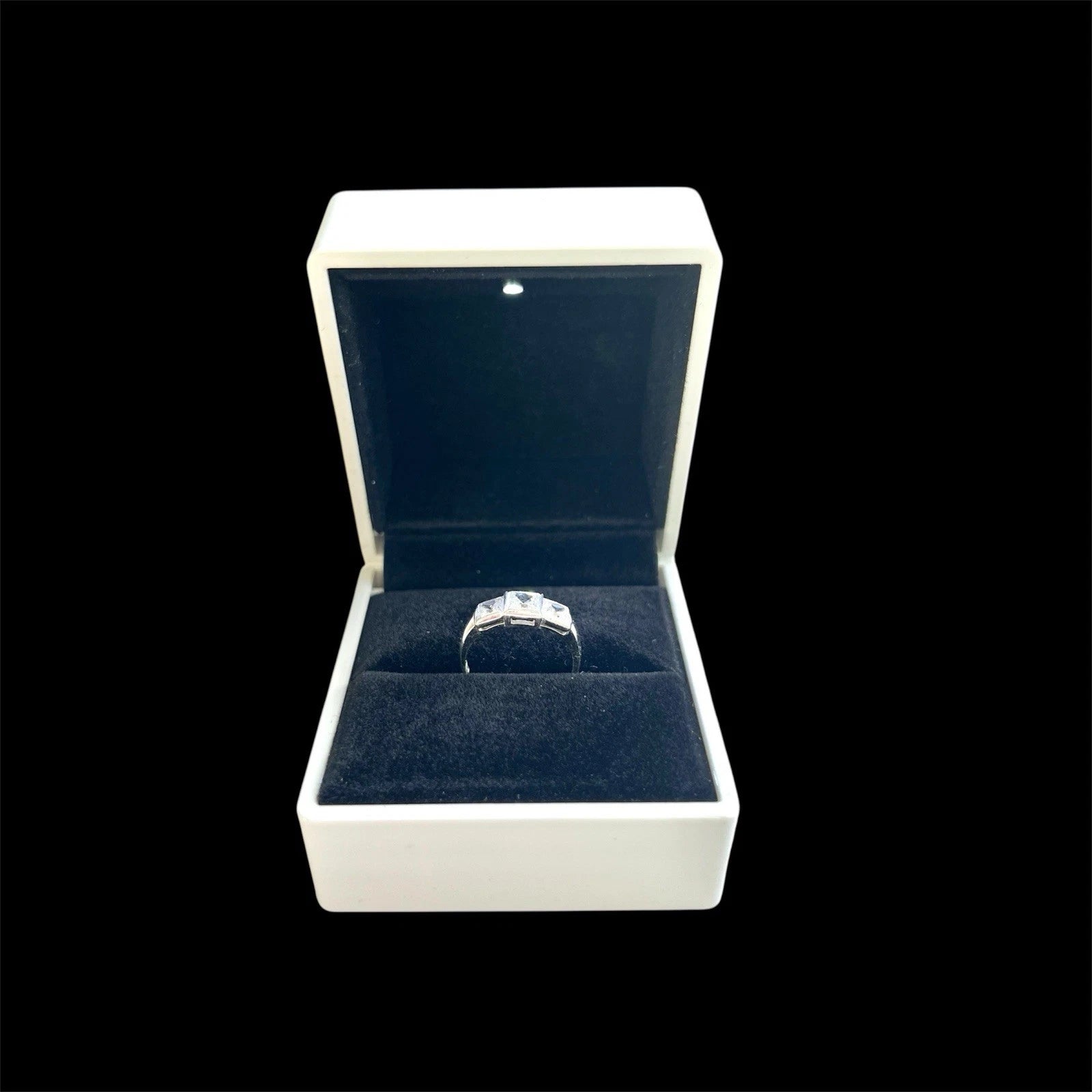 White gold ring in a white jewellery box with a black background