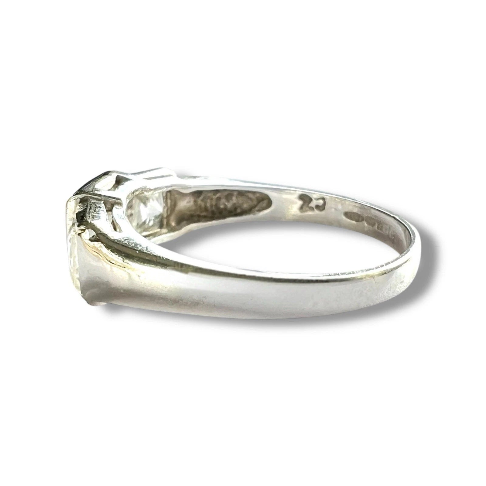 White gold ring with a clear gemstone on a white background, side view 
