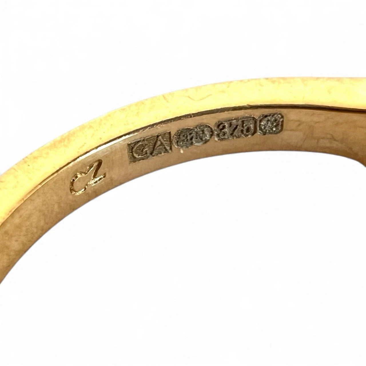 Gold ring with visible hallmark on a white background