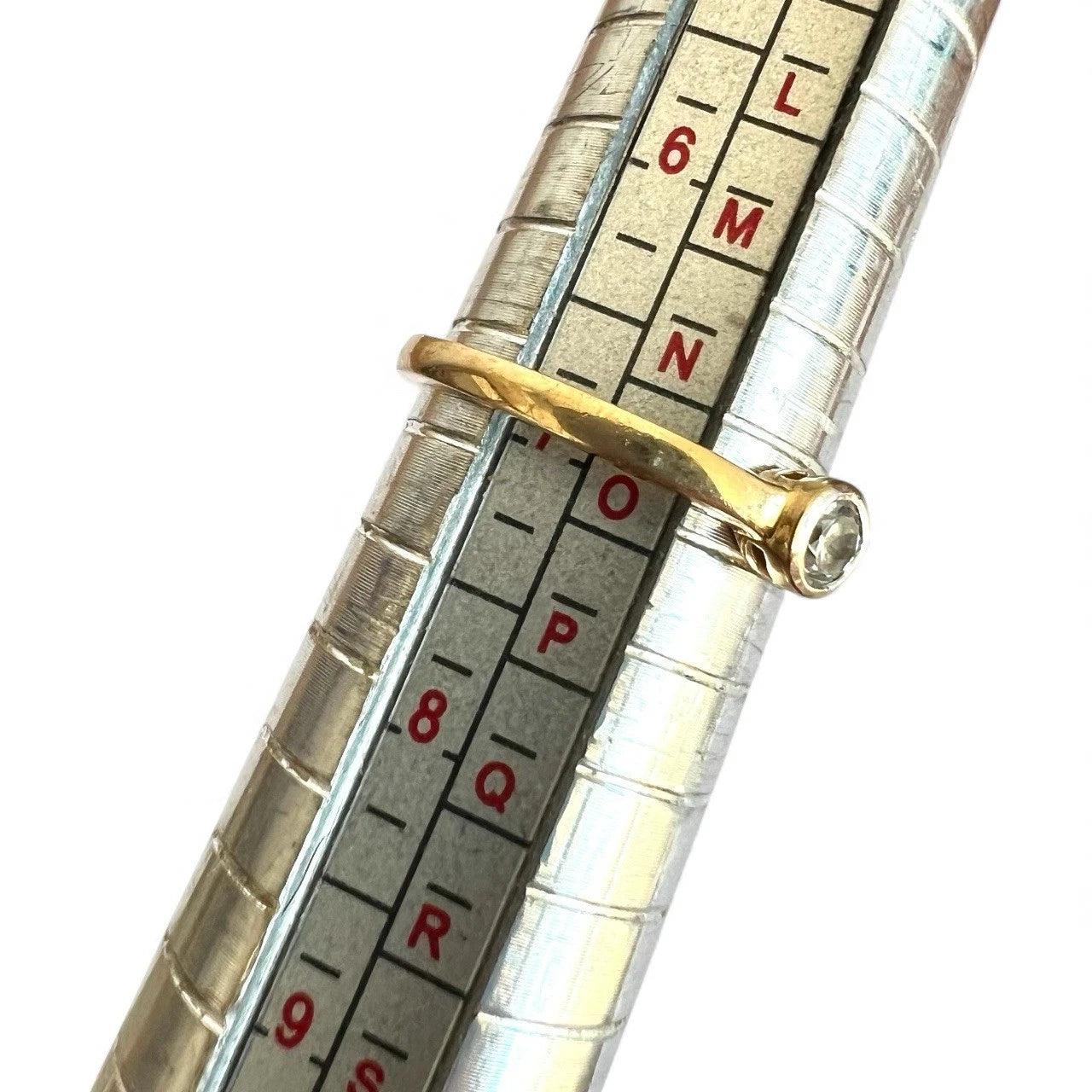 Close-up of a ring on ring sizer gauge on white background