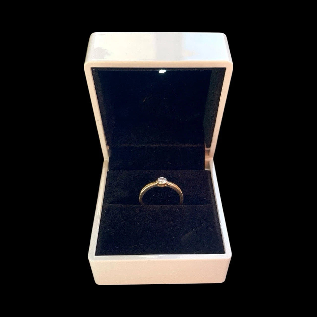Gold ring in an open jewelry box on a black background