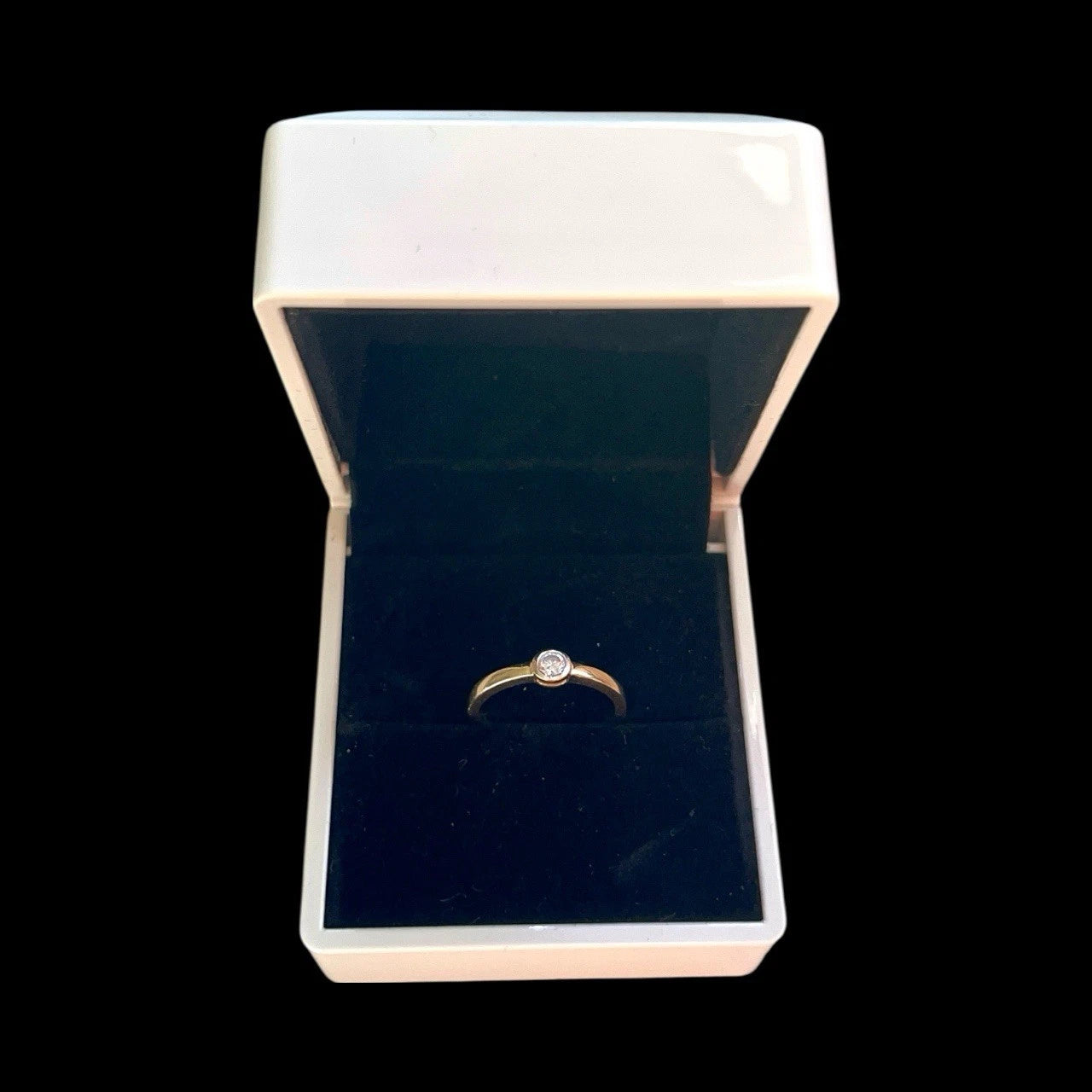 Gold ring with a cubic zirconia in an open jewellery box on a black background