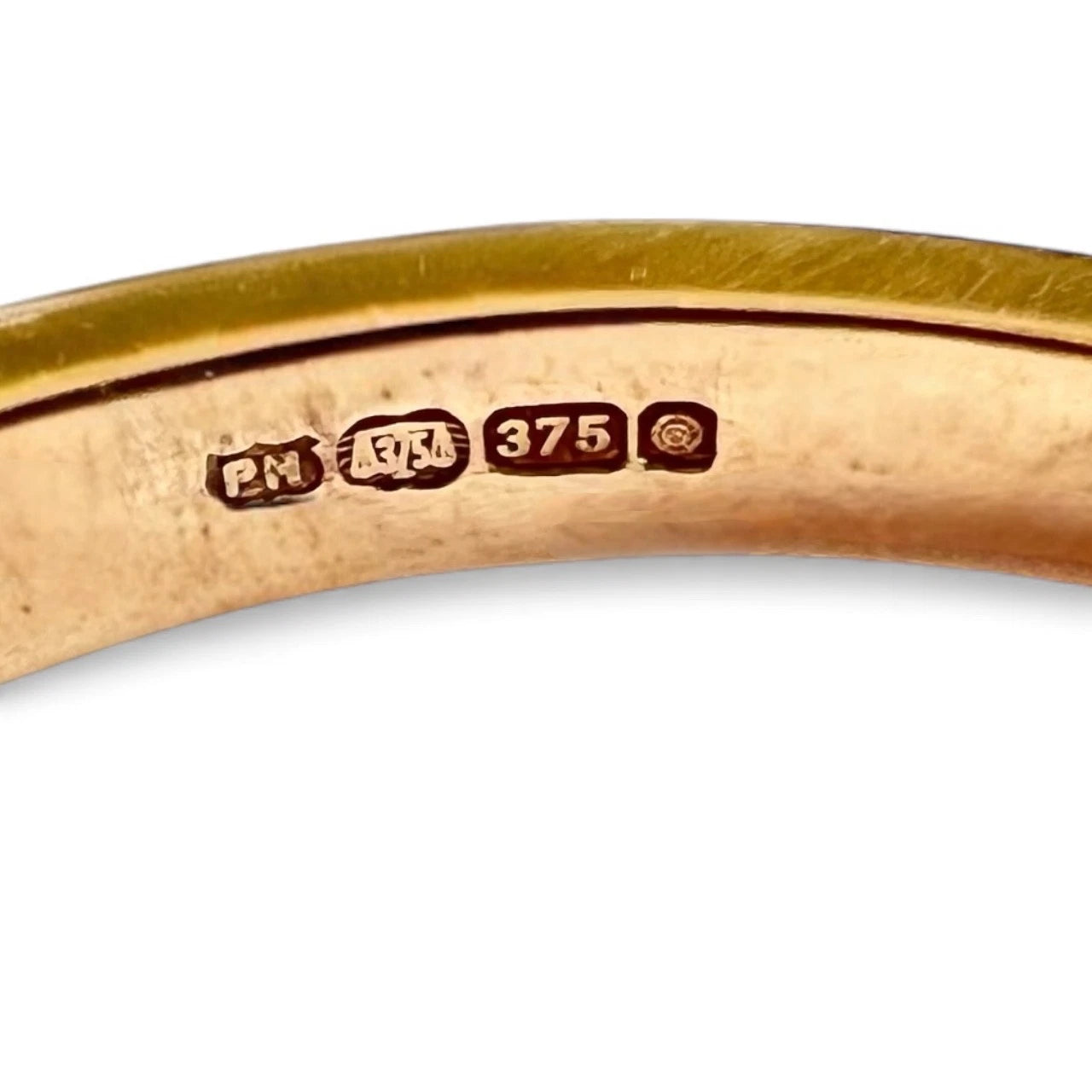 Close-up of a gold ring with visible hallmarks on a white background
