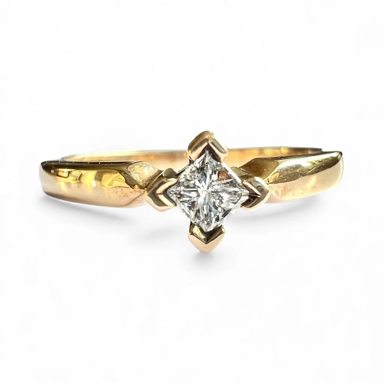 Close up front view of gold ring with a diamond on a white background