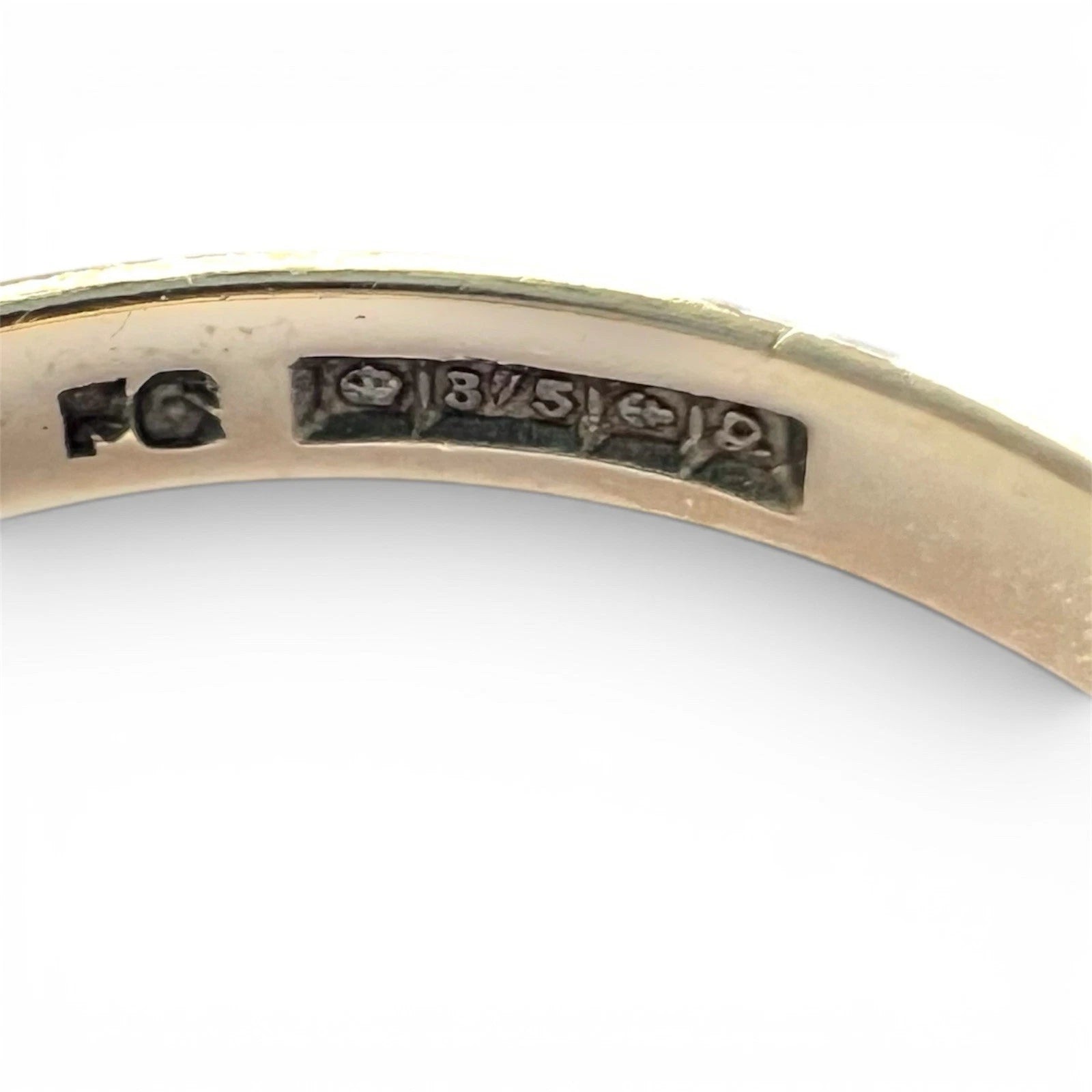 Close-up of a gold ring with engraved hallmark on a white background