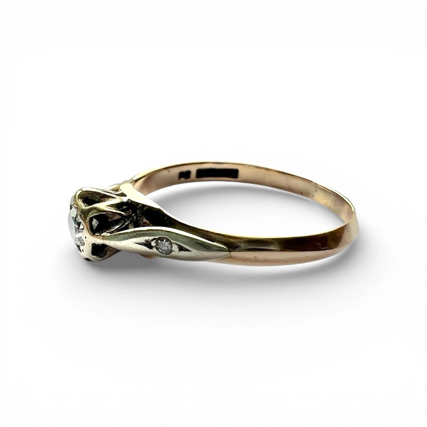 Gold ring with diamond accents on a white background close up side view