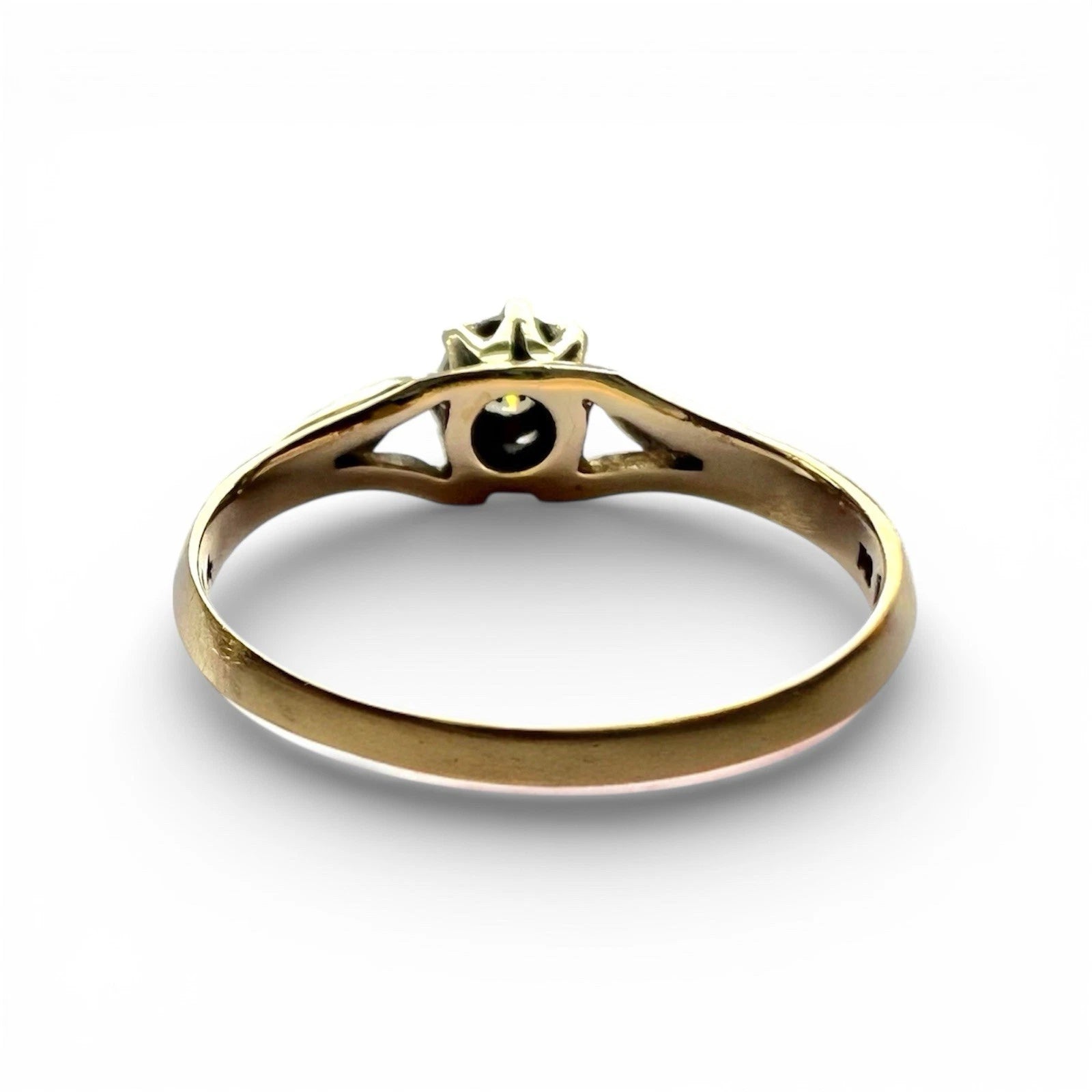 Gold ring with a diamond on a white background rear view of setting and gold band close up 
