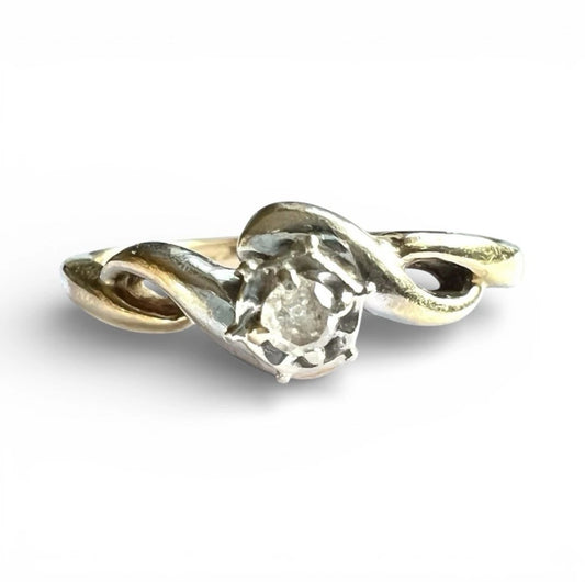 Gold ring with a central diamond on a white background, close up front view of setting 