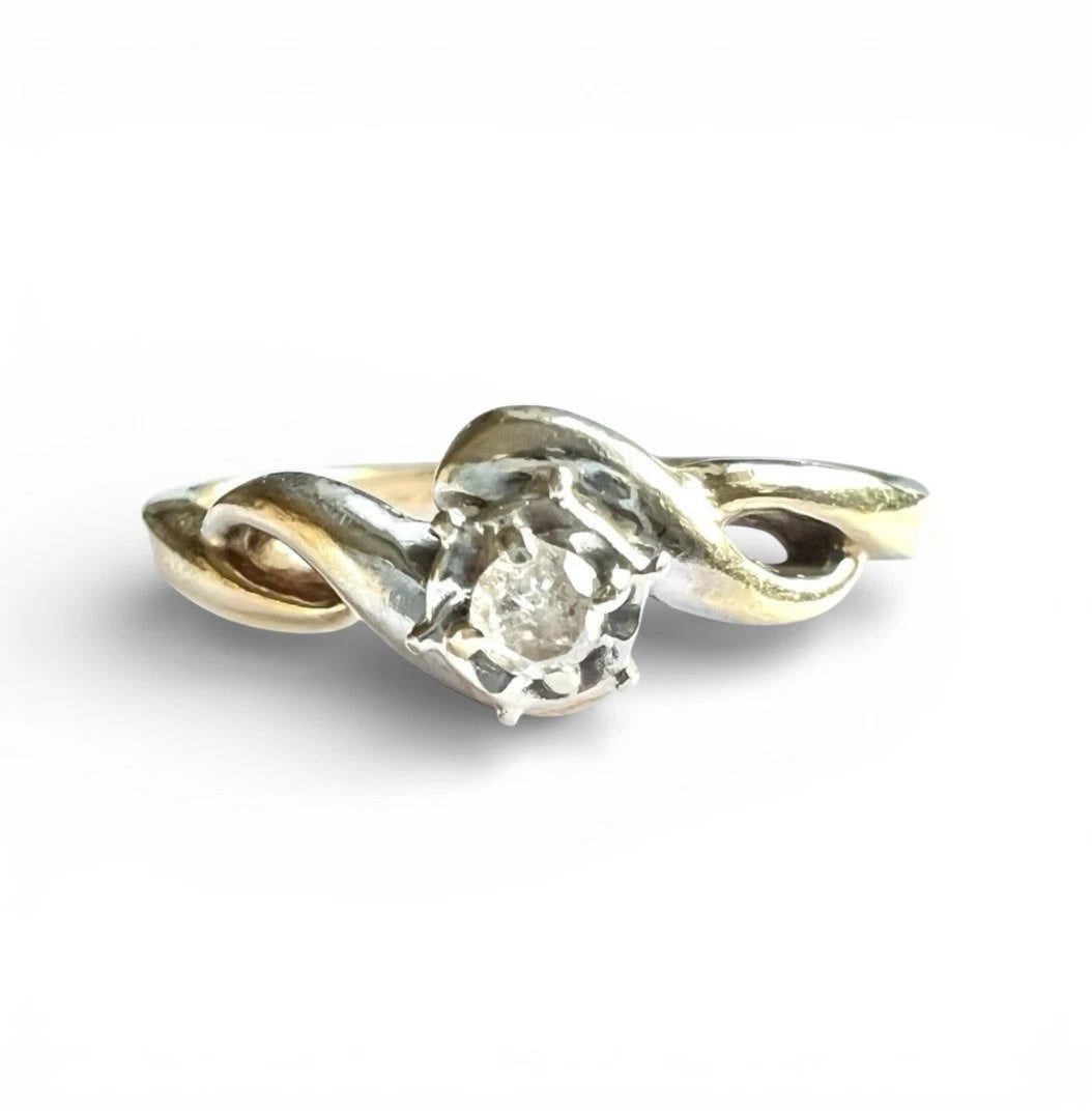 Close-up front view of gold solitaire ring with a diamond on a white background