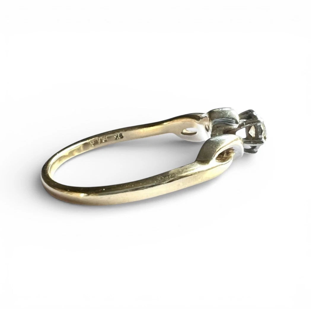 Close up side view of gold ring with a diamond on a white background 