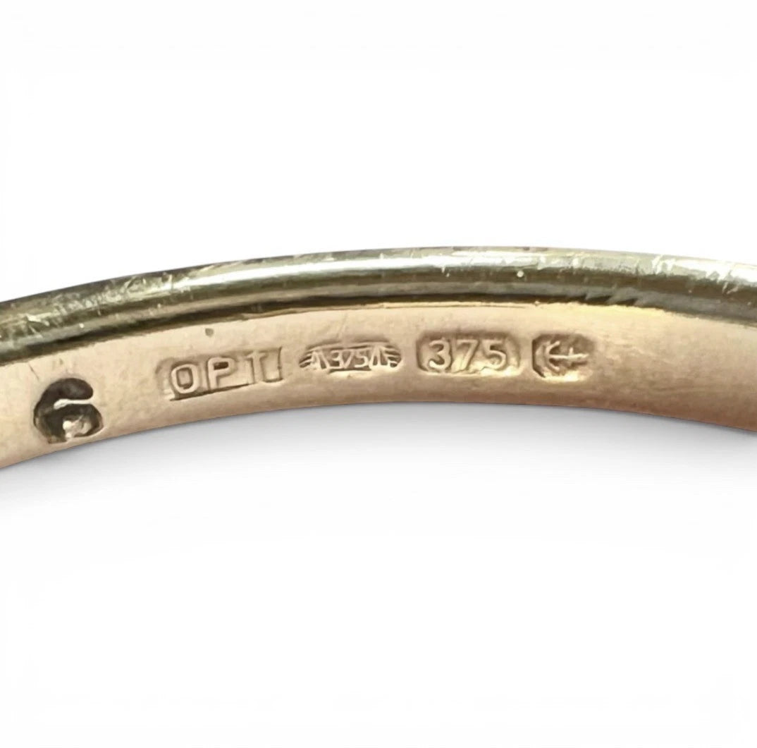 Close-up of a gold ring with visible hallmarks on a white background