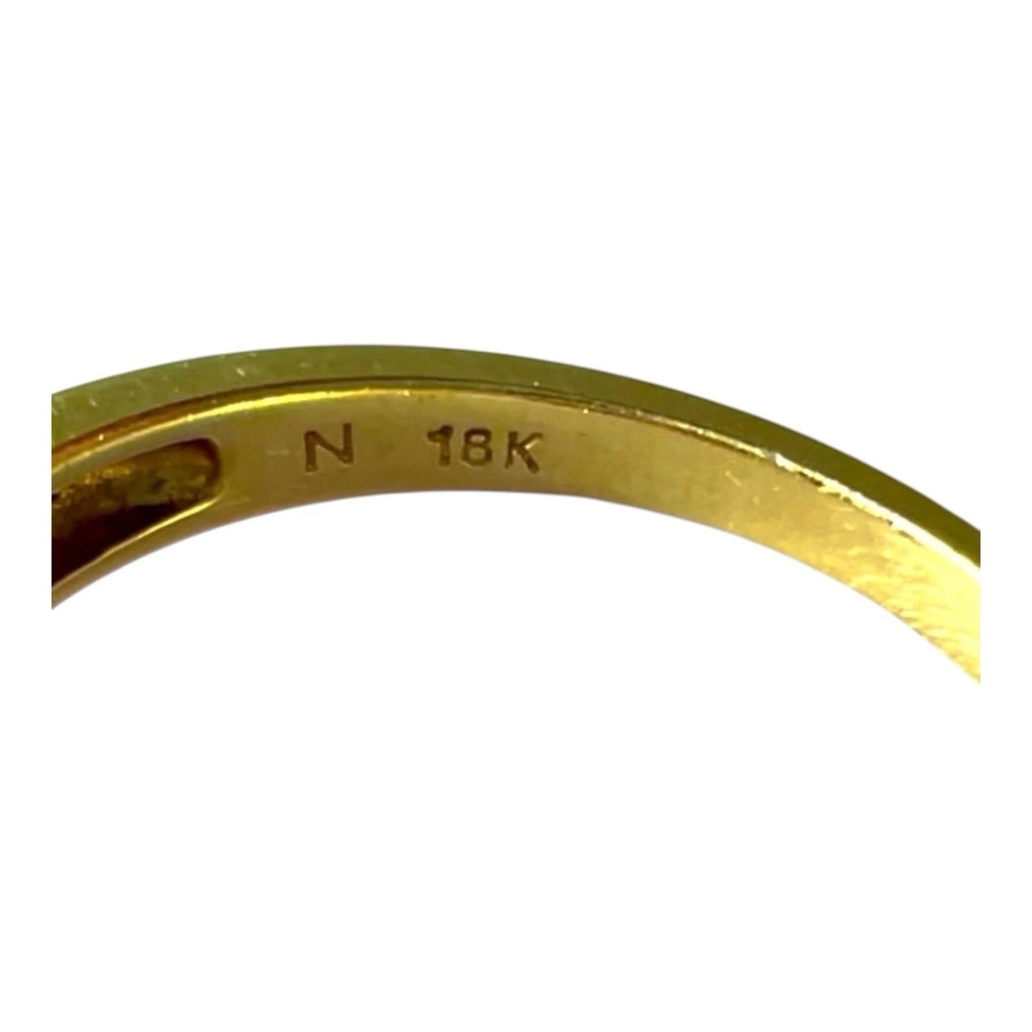 Close-up of a gold ring with 'N 18K' engraving on a white background
