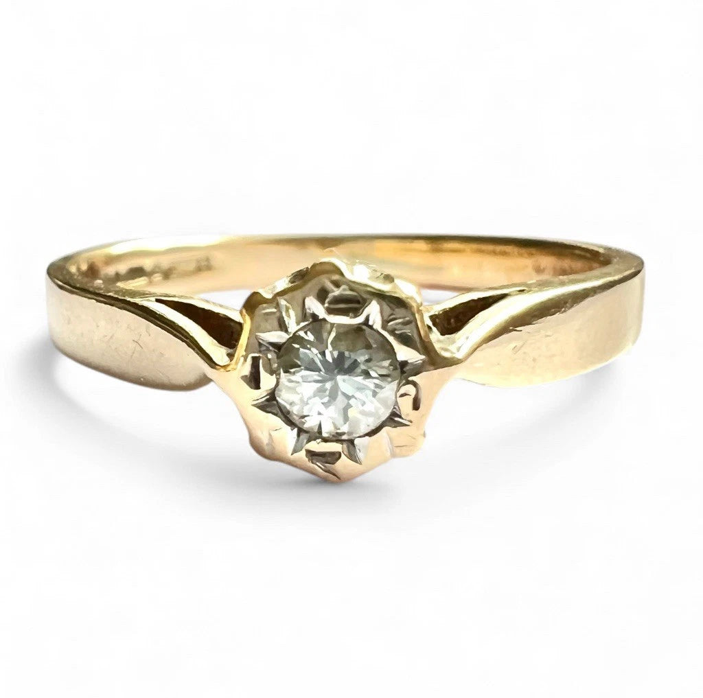 Close up gold solitaire ring with a diamond on a white background