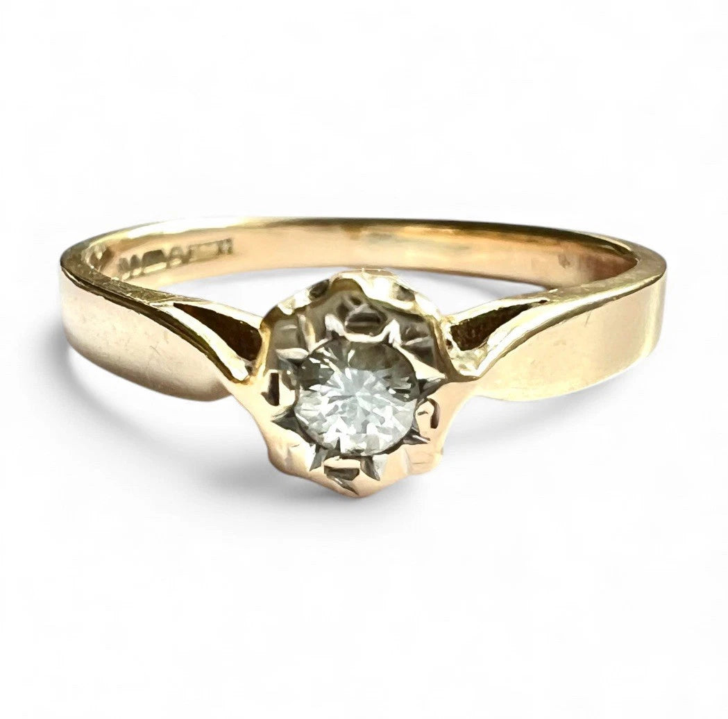 Gold ring with a diamond solitaire on a white background