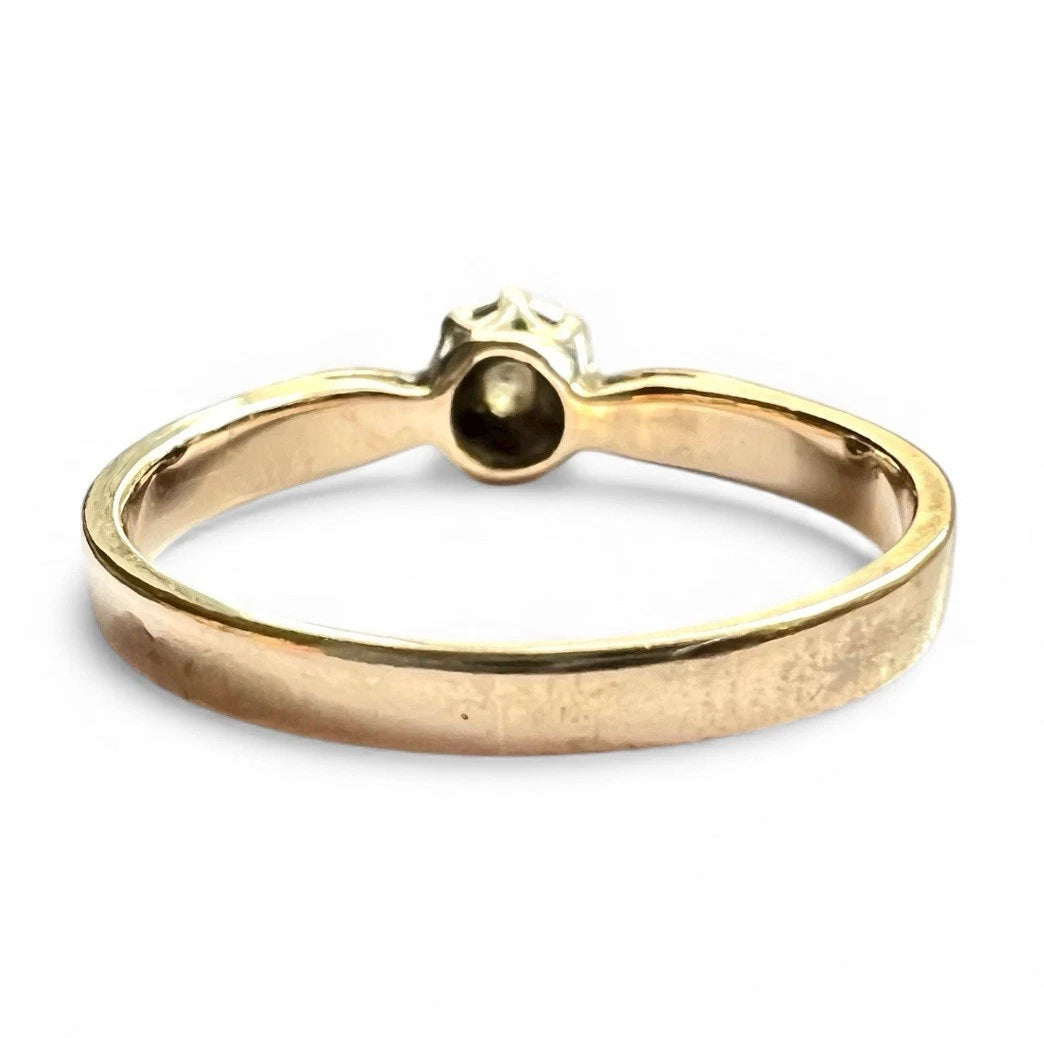 Gold ring with a diamond on a white background. Close up rear view of setting and gold band. 