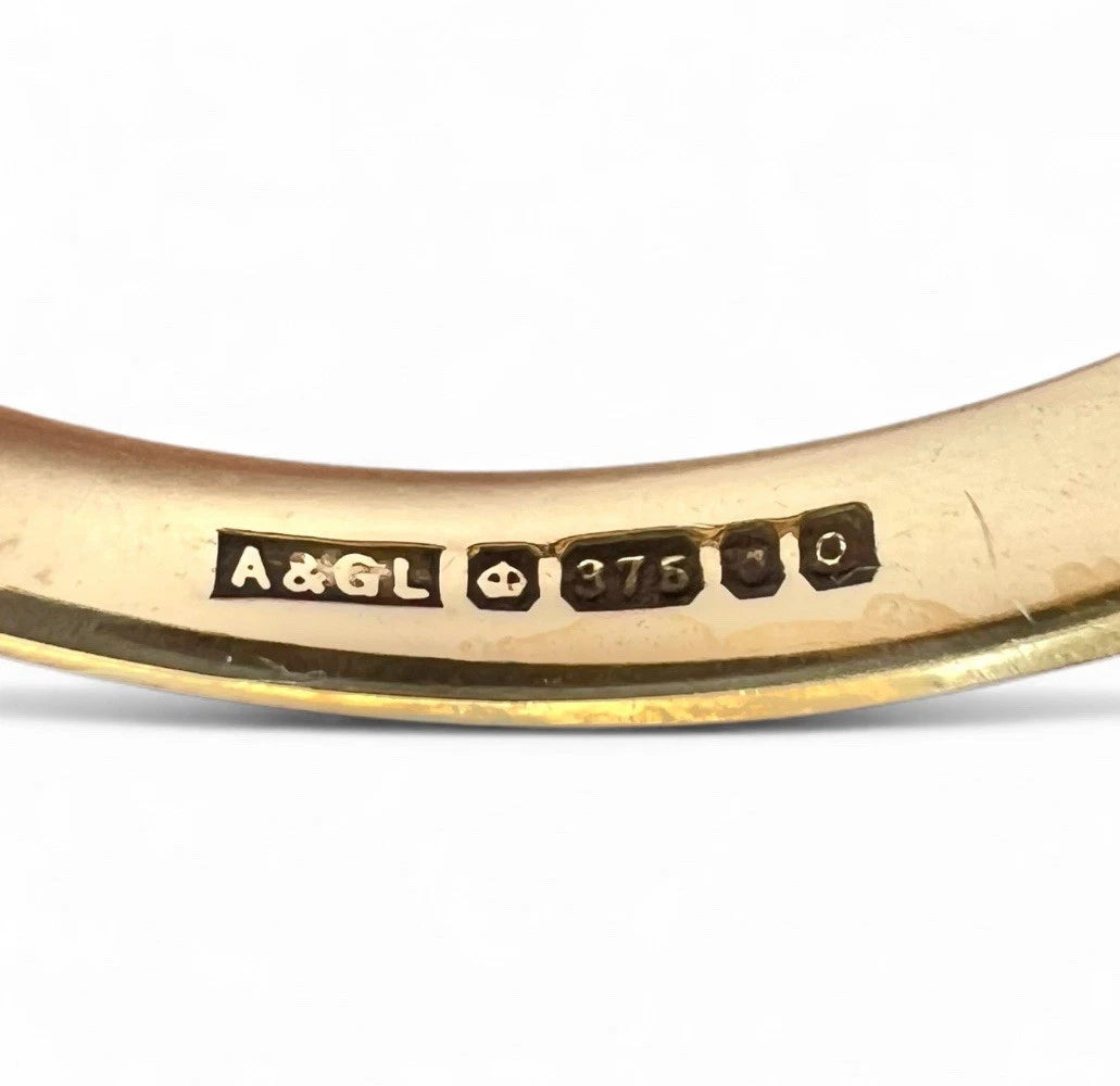 Gold ring with engraved 9ct gold hallmark on a white background