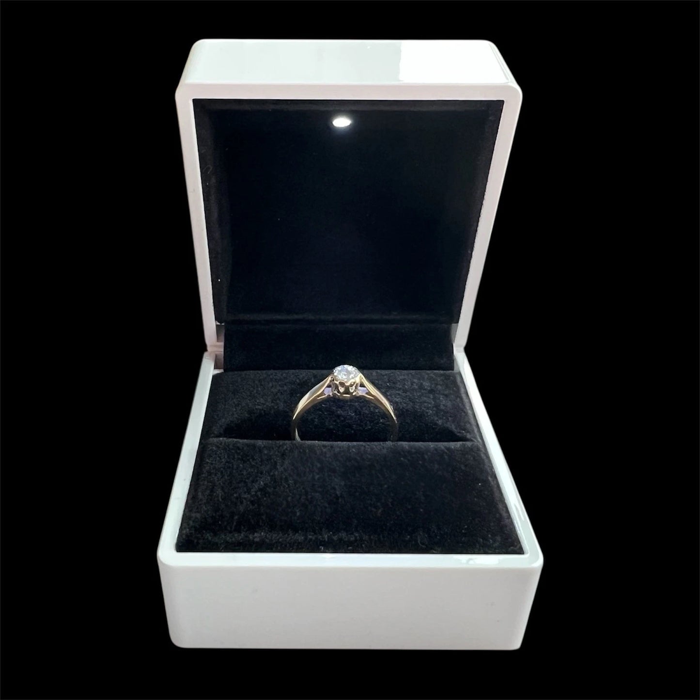 Gold diamond solitaire ring in a white jewellery box with a black interior