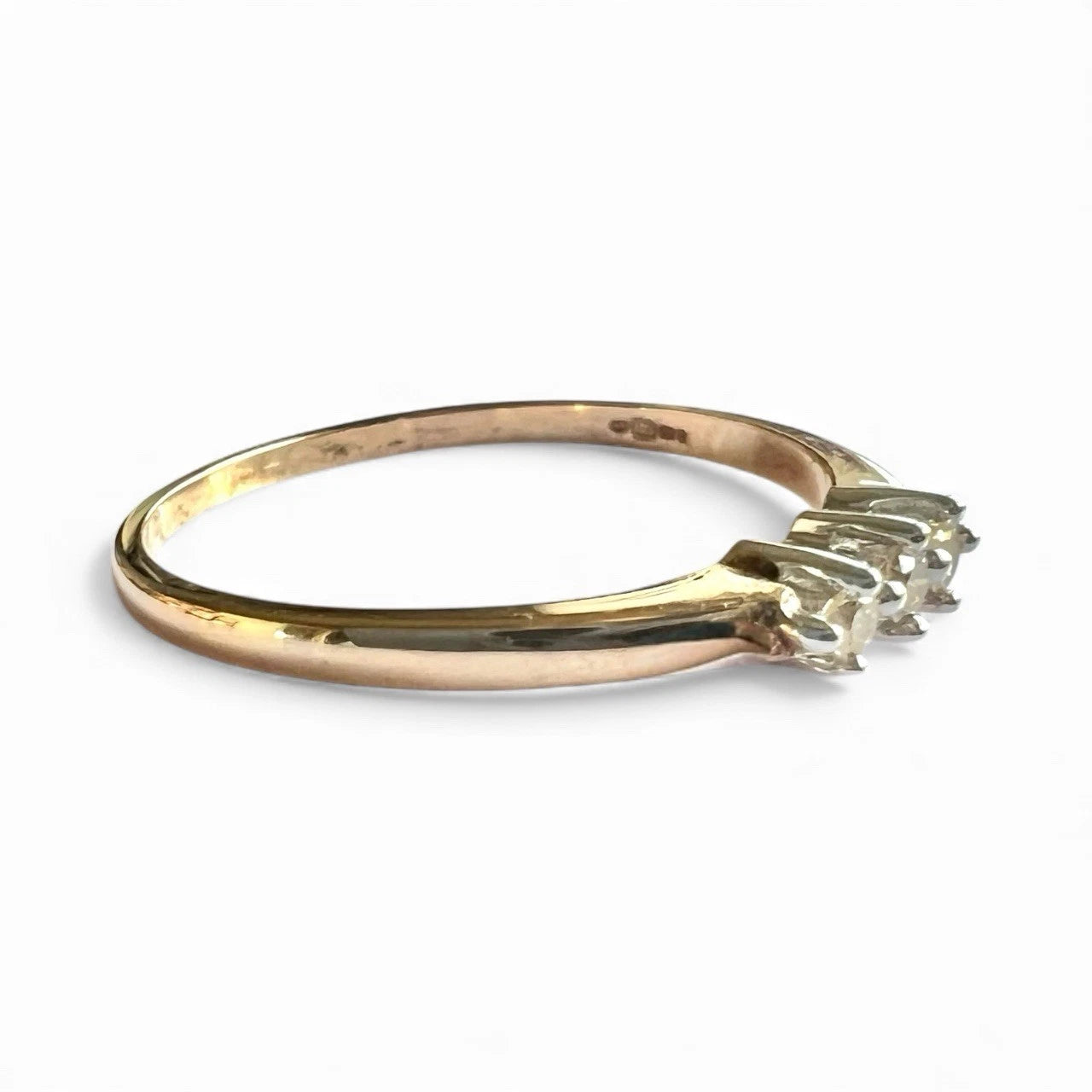 Three stone diamond ring on a white background side view close up