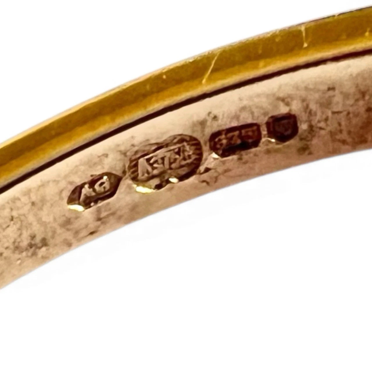 Close-up of a gold ring with engraved hallmark on a white background