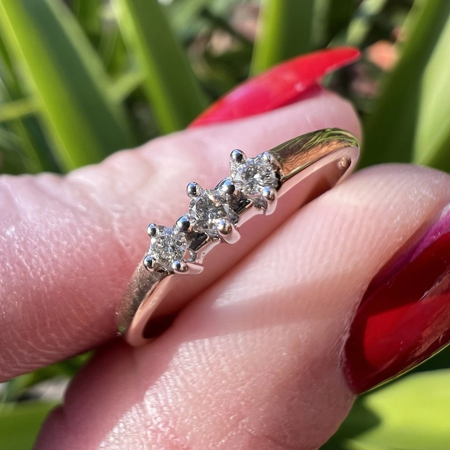  Gold ring with diamonds on a finger against a blurred natural background