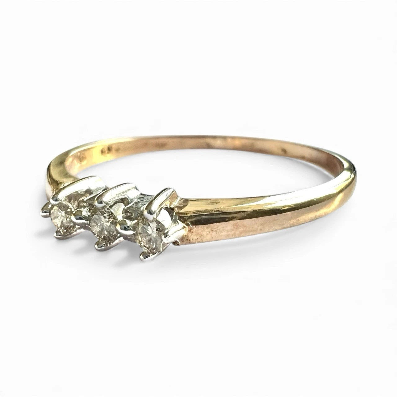 Gold ring with three diamonds on a white background. Close up side view 