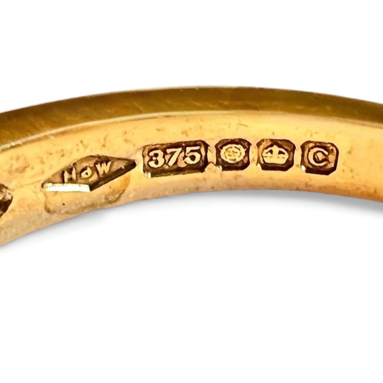 Close-up of a gold ring with engraved hallmark on a white background