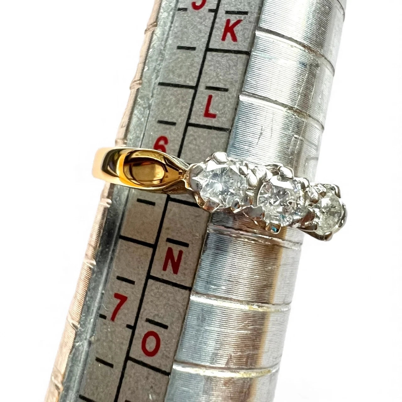 Gold and diamond ring on a ring size guage for size measurement