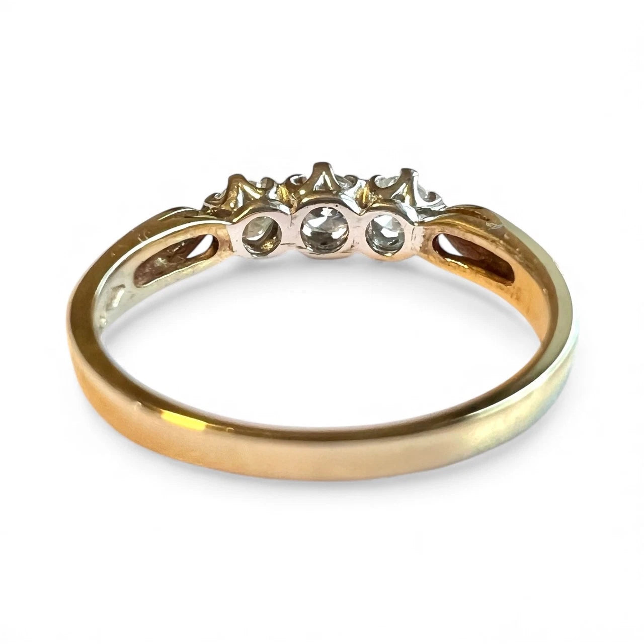 Gold ring with three diamonds on a white background. Close up rear view of setting and old band 