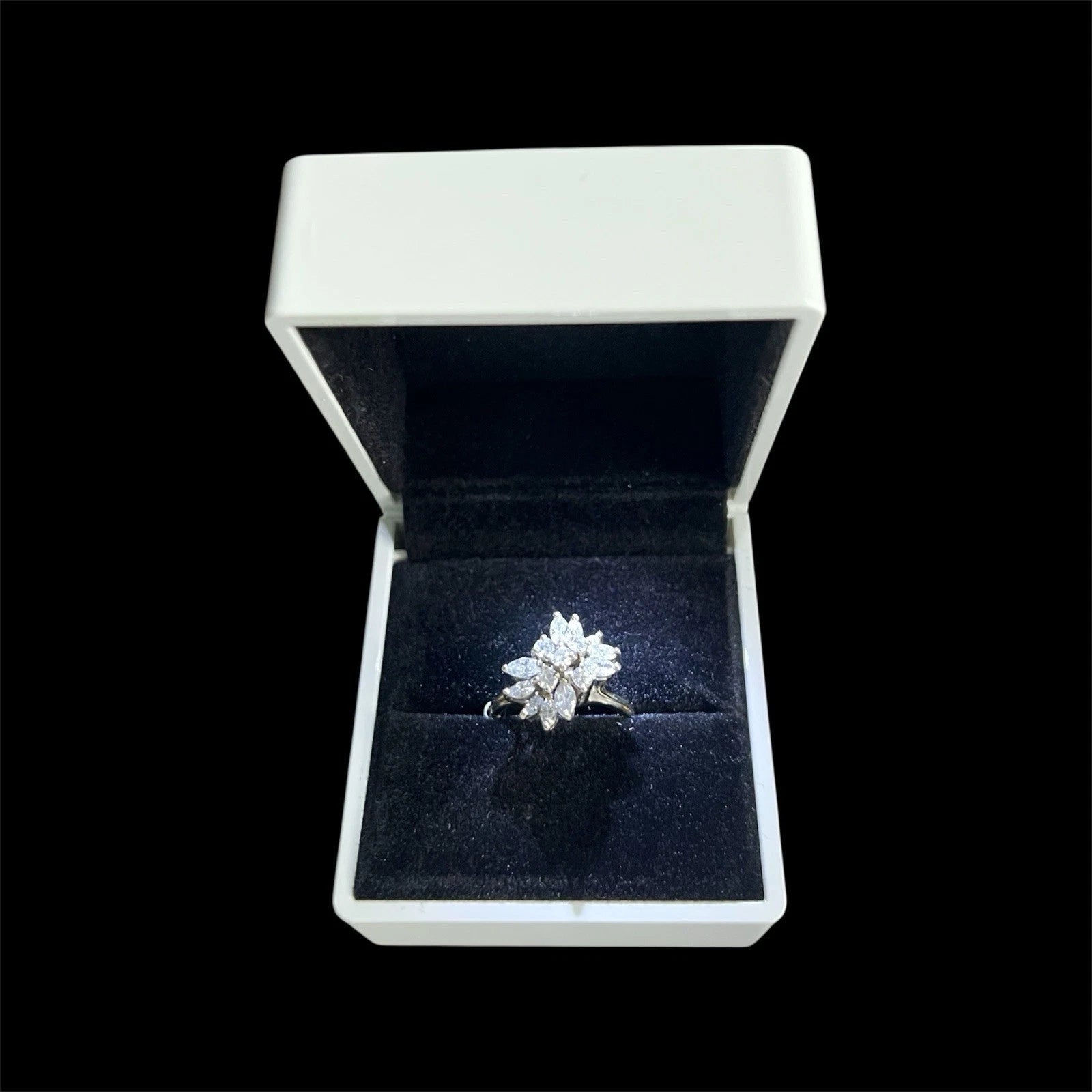 Diamond cluster ring in an open jewellery box on a black background