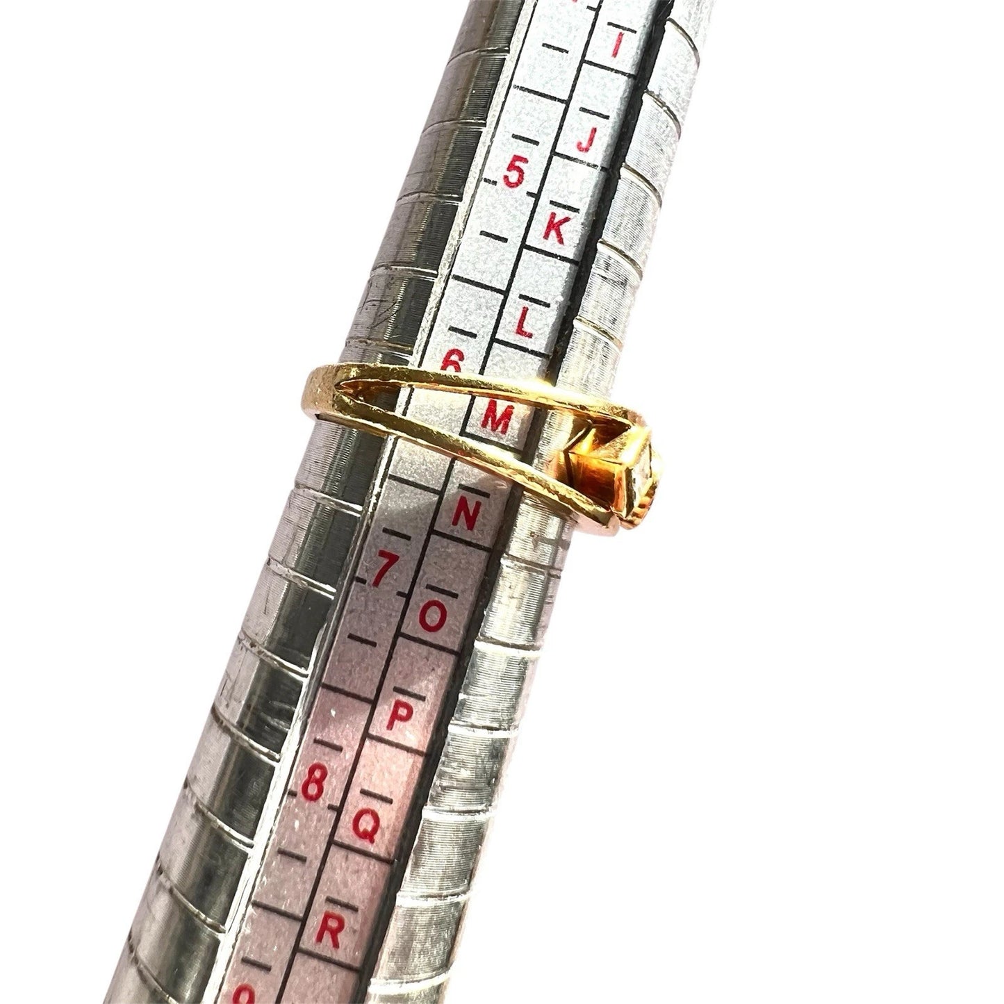 Metallic measuring gauge with a gold diamond ring on a white background