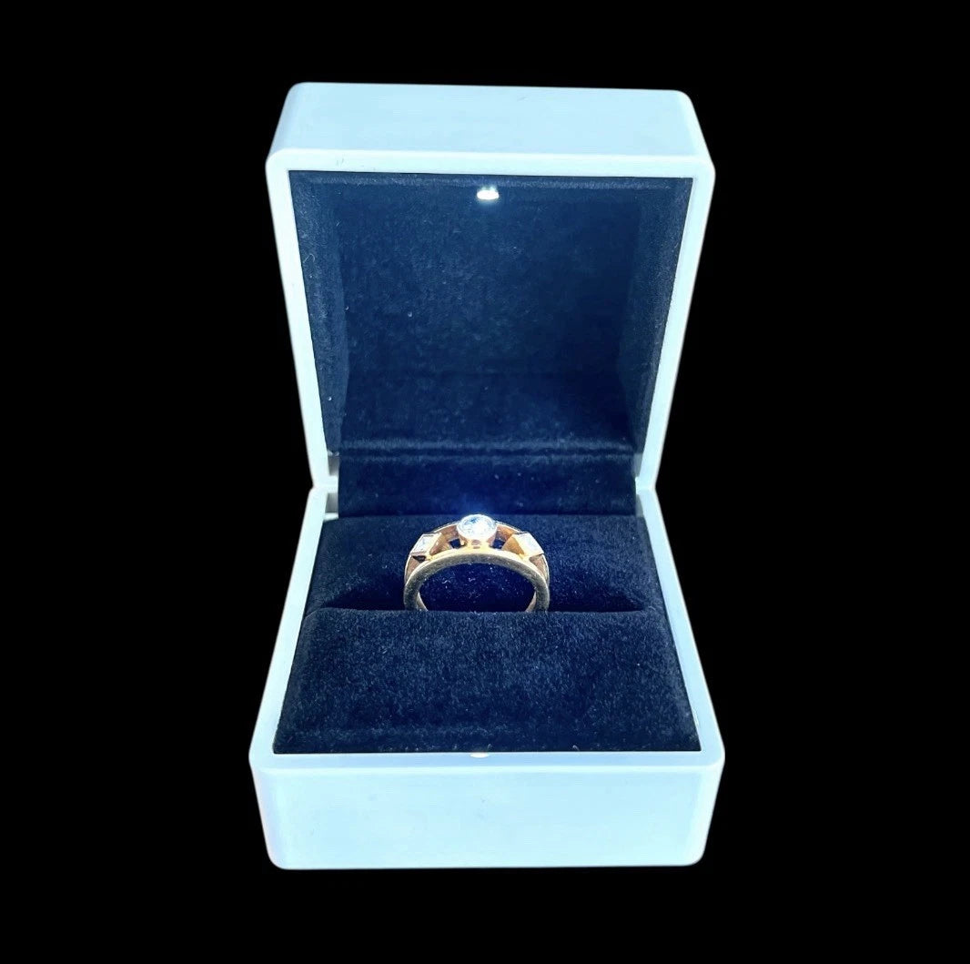 Gold ring with a diamond in a white jewellery box on a black background