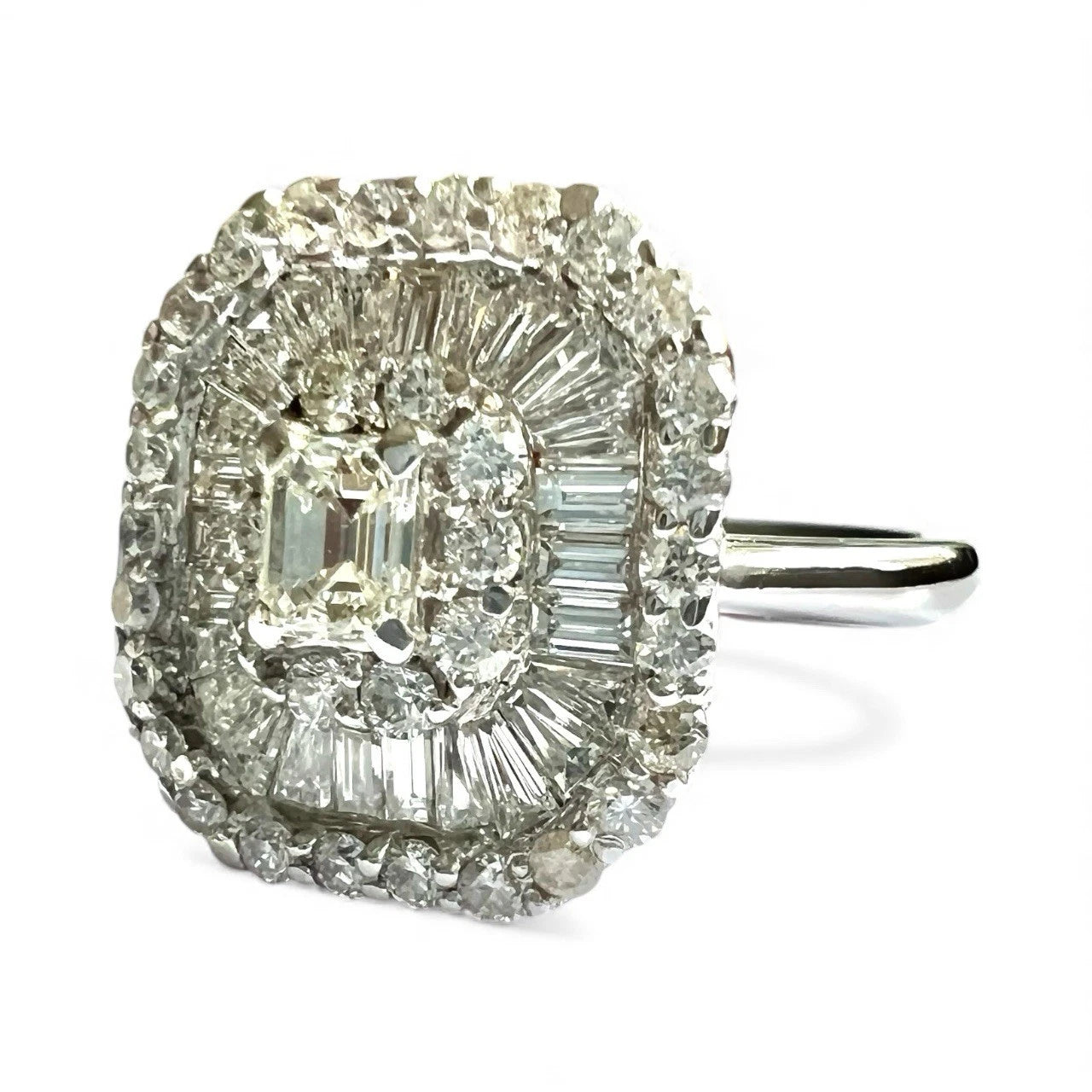 Diamond ring with a central emerald-cut diamond and baguette diamonds on a white background