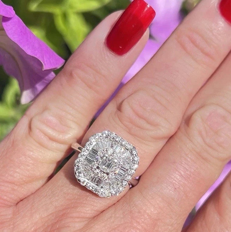 Diamond ring on a hand with red nail polish against a blurred floral background