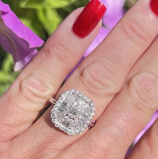 Diamond ring on a hand with red nail polish against a blurred floral background