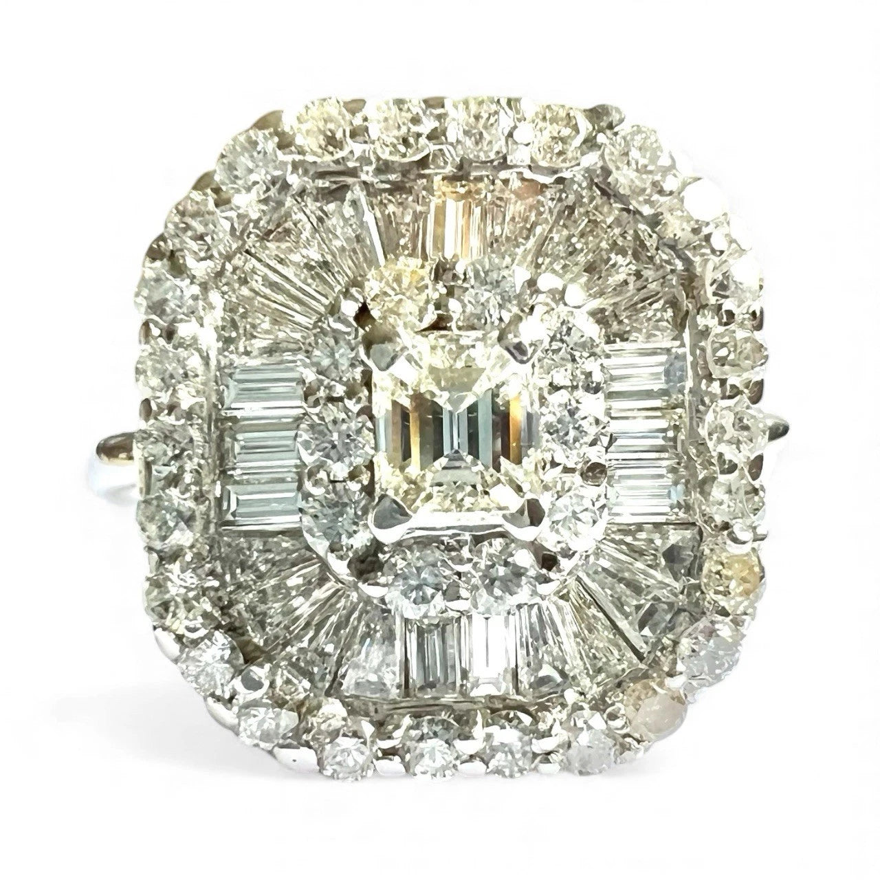 Diamond ring with a central emerald-cut diamond and baguette diamonds on a white background