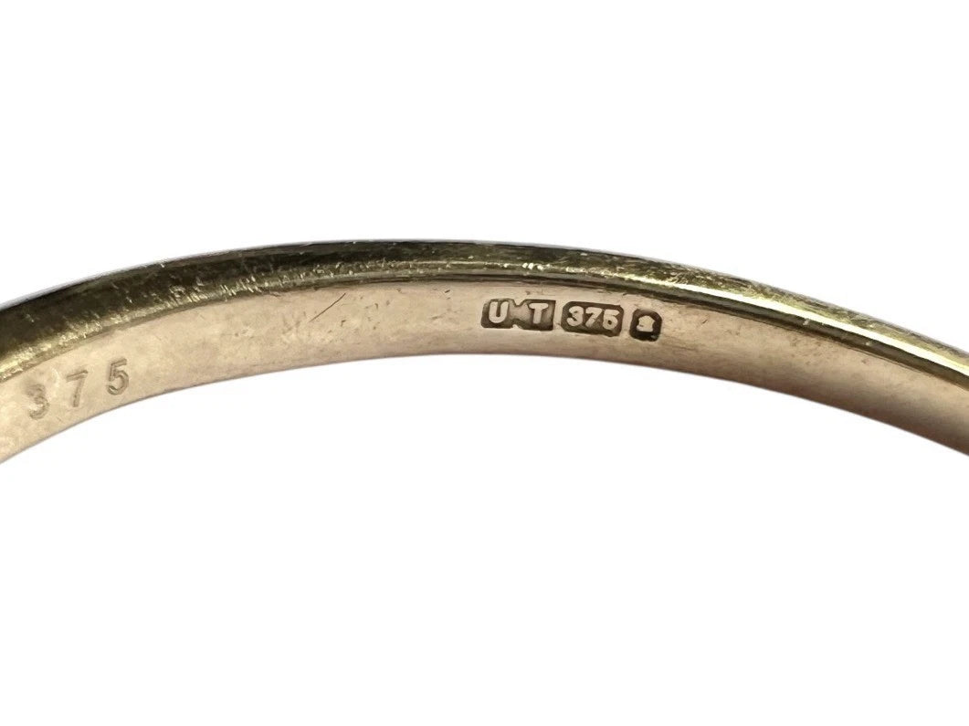 Close-up of a gold ring with visible hallmarks on a white background