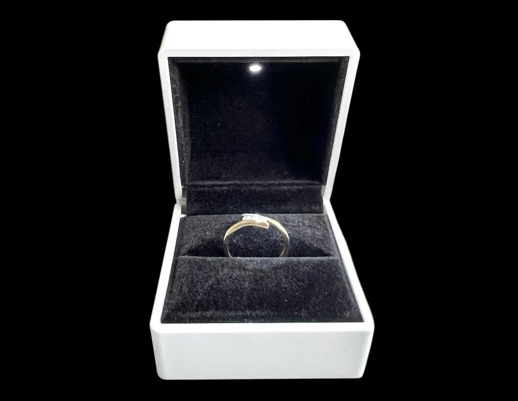 Gold diamond three stone ring in a white jewellery box on a black background