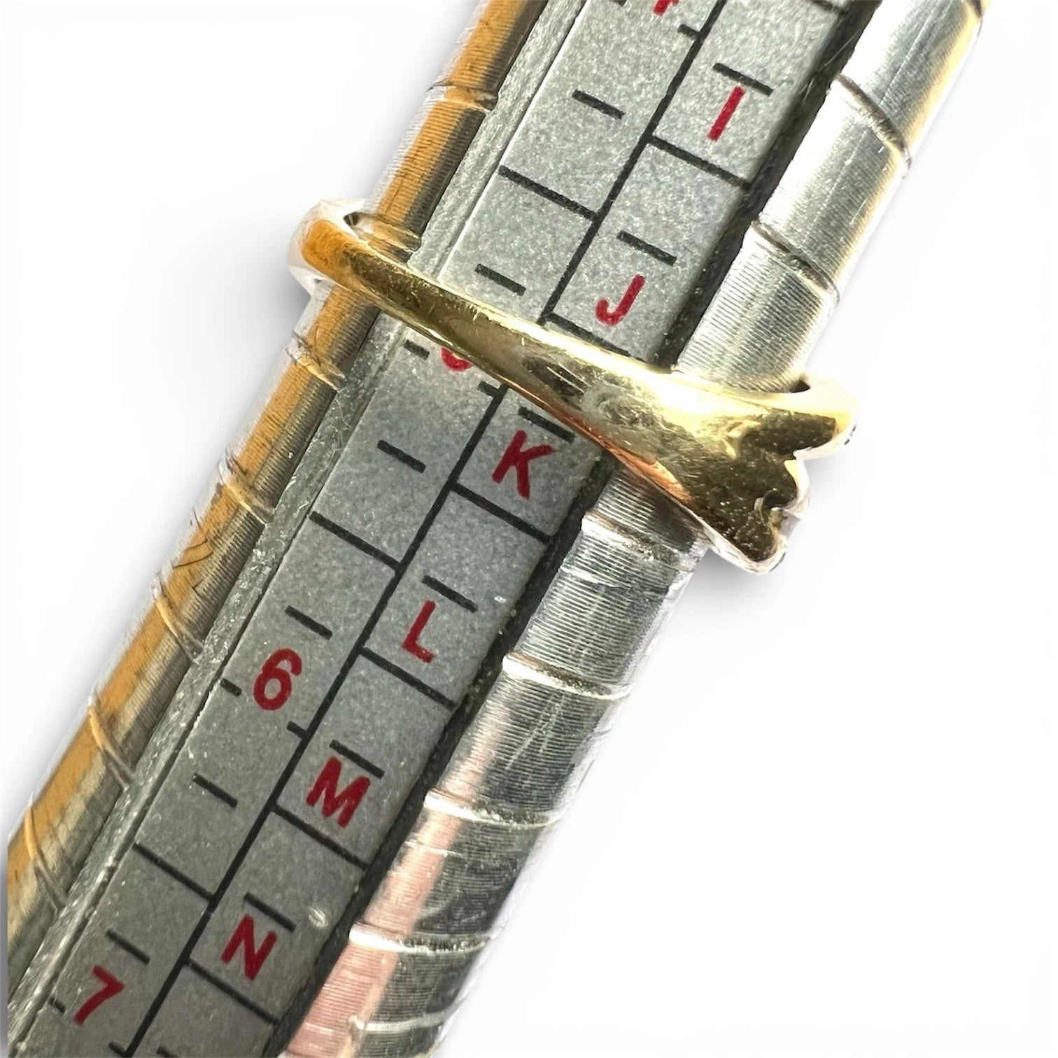 Close-up of a metallic measuring tool with gold band and measurement scale.