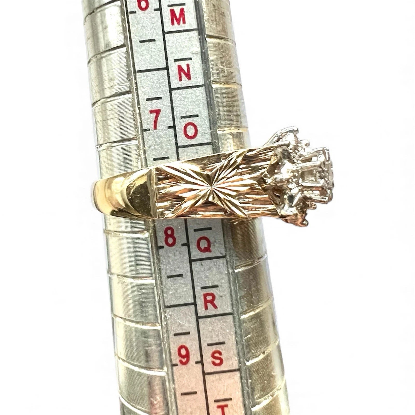 Gold ring with diamond on a ruler for size reference