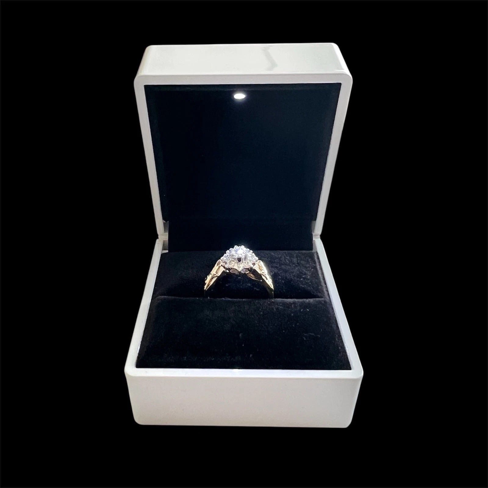 Gold ring with a diamond in an open jewelry box on a black background