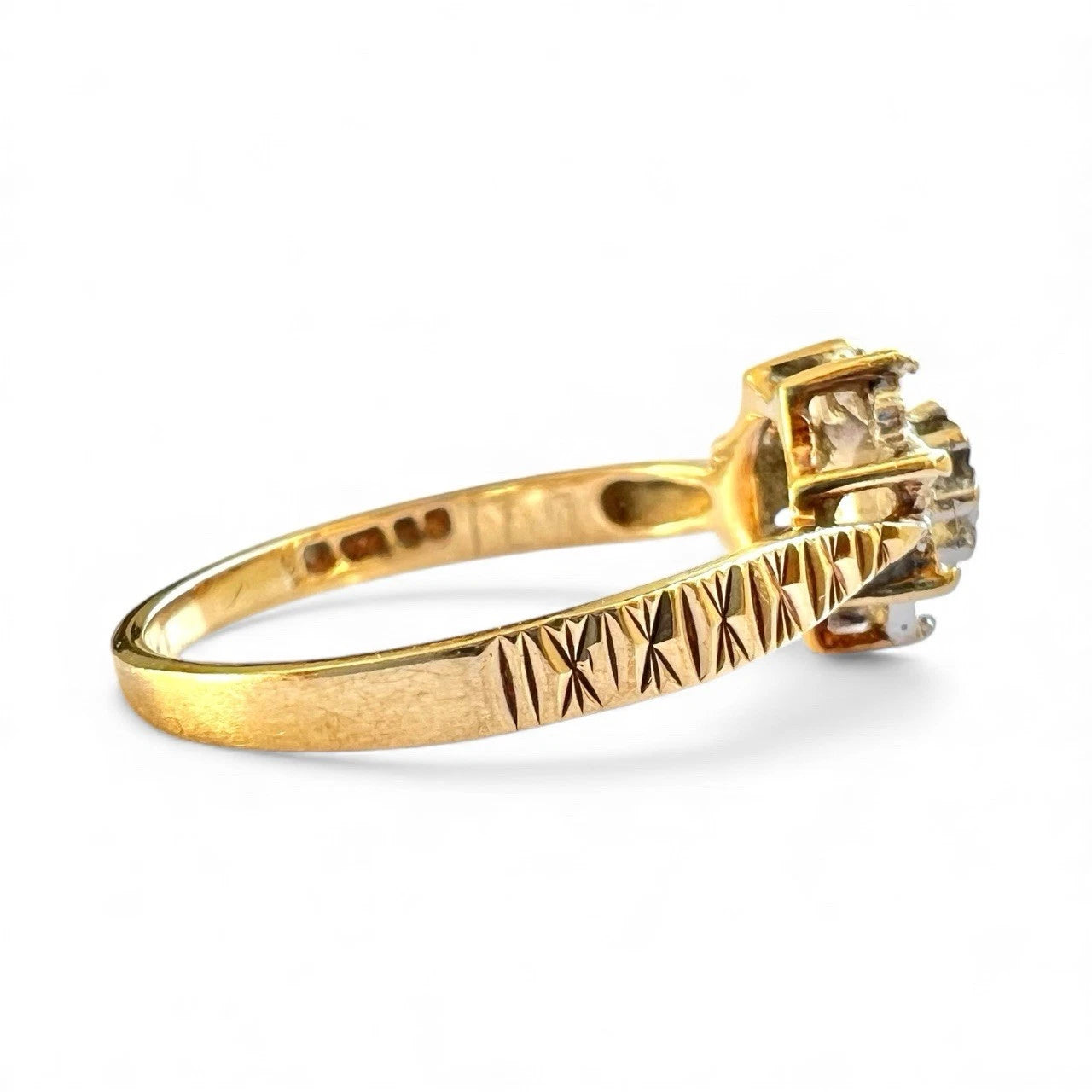 Gold ring with a diamond and textured band on a white background, close up top down view  