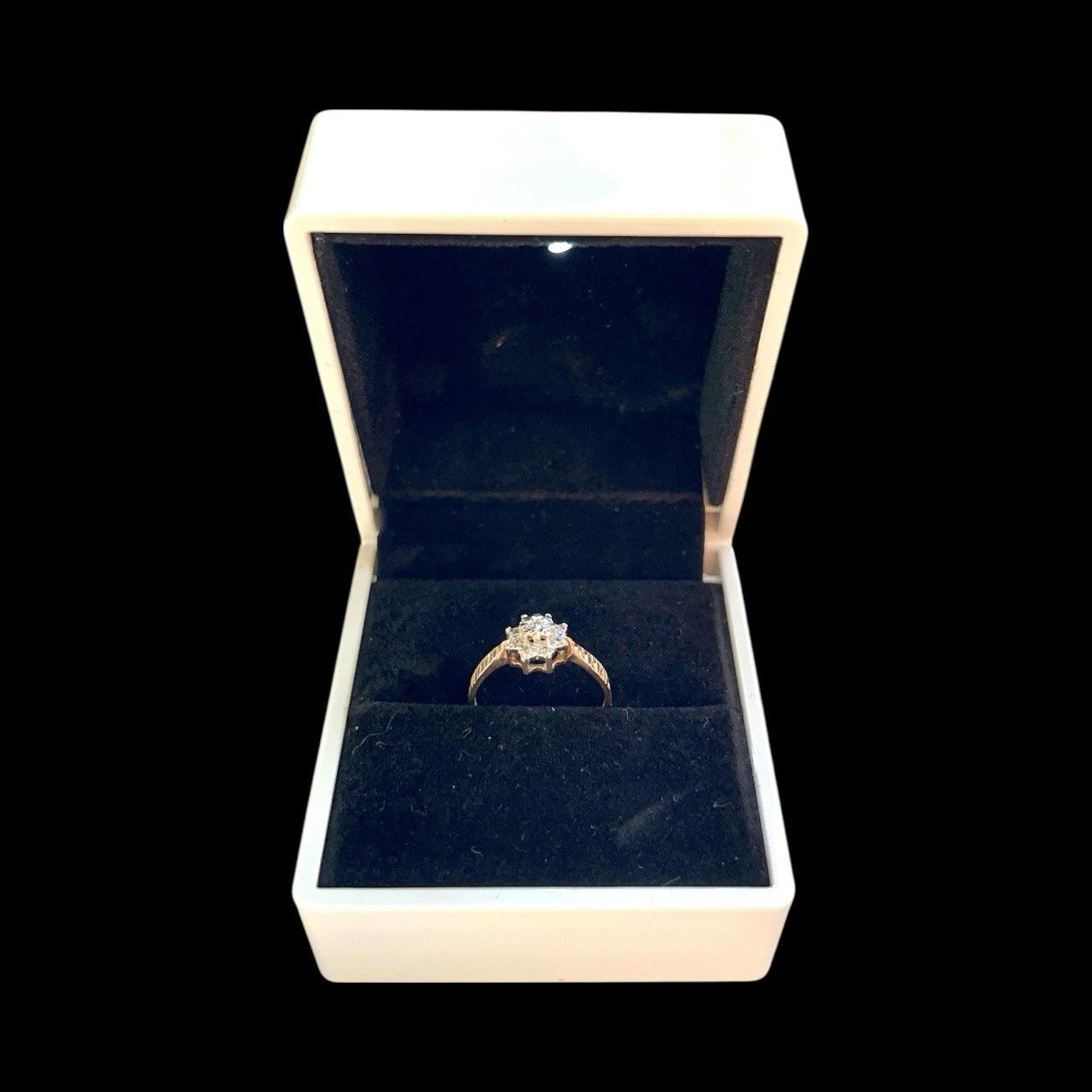 Gold diamond clutter ring with a diamond in an open jewellery box on a white background